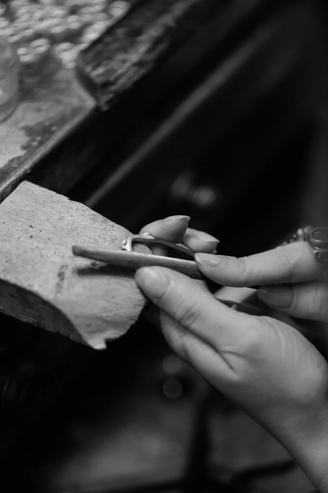 Detail of hands shaping a ring on a leather plate.